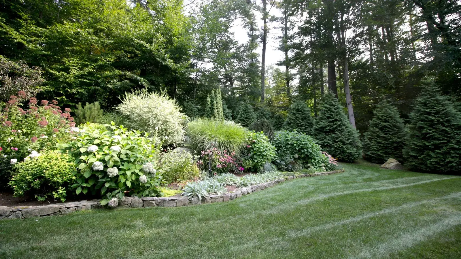 Planted garden beds beside a striped lawn on a BREN Landscaping property